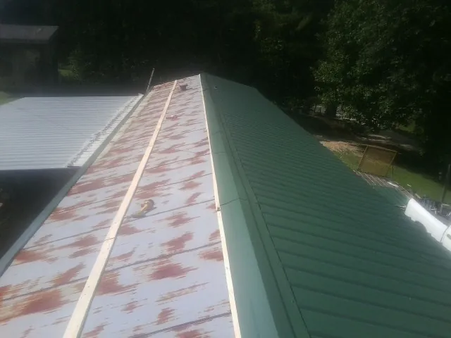 Old rusted panels beside newly installed green metal roofing — Wind Damage Roof Repair by Roofing Brothers in Rehoboth