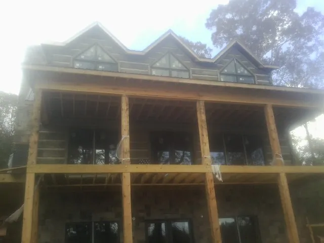 Dormers and porch framing on a large log home under construction — Roof Coating work by our crew in Rehoboth