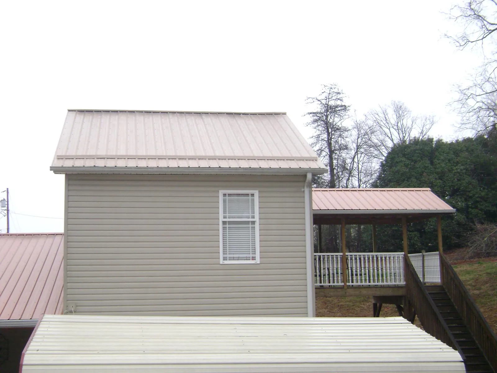 Tan metal roofs on a two story addition and attached porch, from a Roof Replacement job in Rehoboth